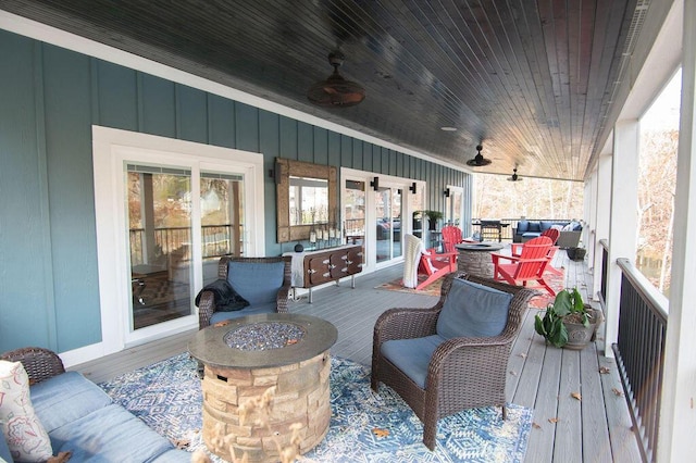 wooden deck featuring ceiling fan and an outdoor living space with a fire pit