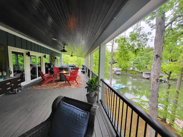 wooden terrace featuring a water view and an outdoor fire pit