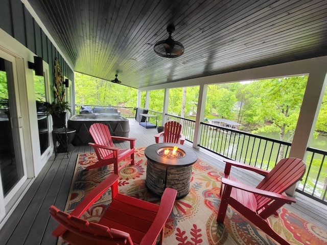 deck with ceiling fan, area for grilling, covered porch, and an outdoor fire pit