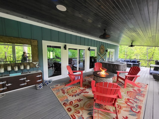 wooden deck with covered porch, ceiling fan, and an outdoor living space with a fire pit