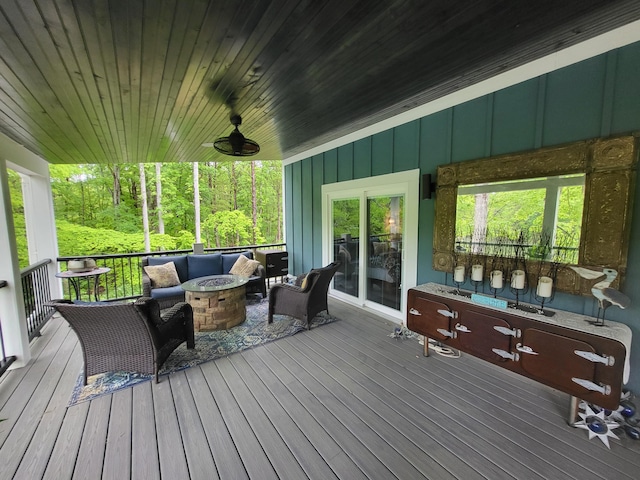 wooden terrace featuring ceiling fan and an outdoor living space with a fire pit