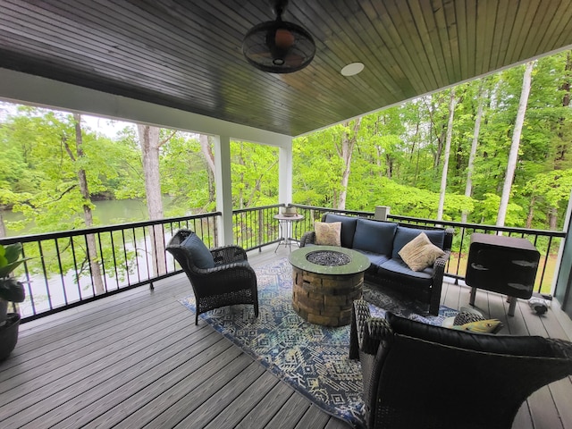 wooden deck featuring ceiling fan and an outdoor living space with a fire pit