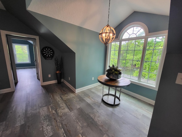 interior space with an inviting chandelier, dark hardwood / wood-style floors, and vaulted ceiling