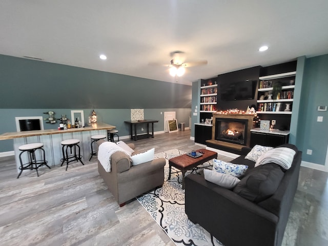 living room featuring ceiling fan, wood-type flooring, built in features, and lofted ceiling