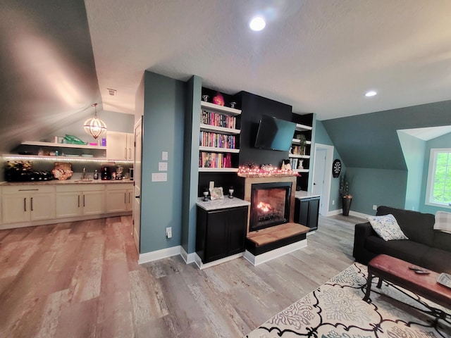 interior space with a textured ceiling, light hardwood / wood-style flooring, and lofted ceiling