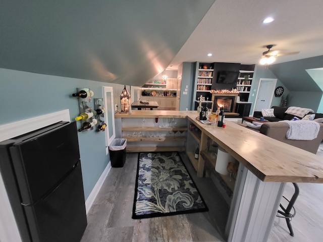 interior space featuring built in shelves, ceiling fan, lofted ceiling, and hardwood / wood-style flooring