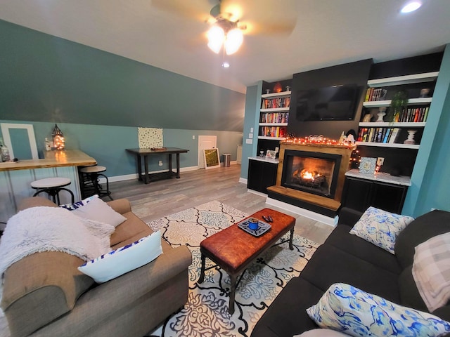 living room featuring light wood-type flooring, built in features, ceiling fan, and lofted ceiling