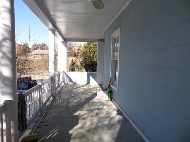 snow covered patio with ceiling fan and a porch