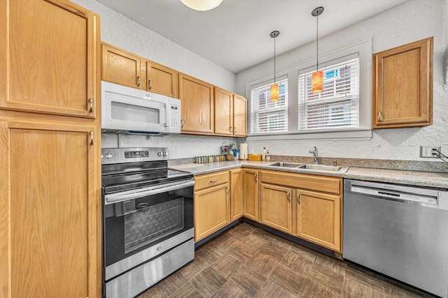 kitchen with pendant lighting, stainless steel appliances, sink, and dark parquet flooring