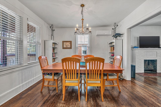 dining area with a wall mounted air conditioner, dark wood-type flooring, a chandelier, and a brick fireplace