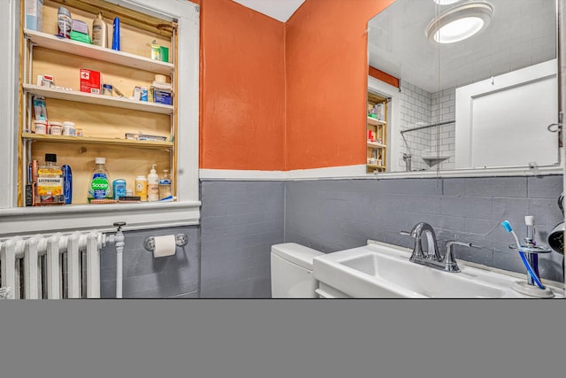 bathroom featuring sink, radiator heating unit, and toilet