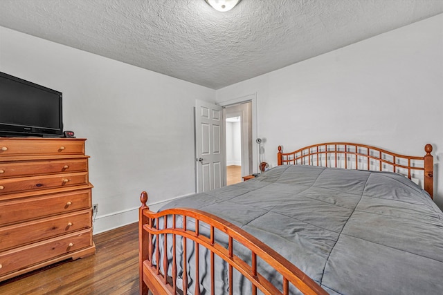 bedroom with dark hardwood / wood-style floors and a textured ceiling