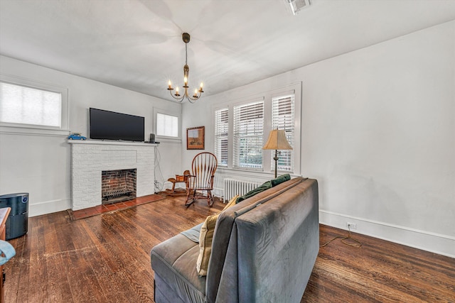 living room with radiator, a chandelier, a fireplace, and dark hardwood / wood-style floors