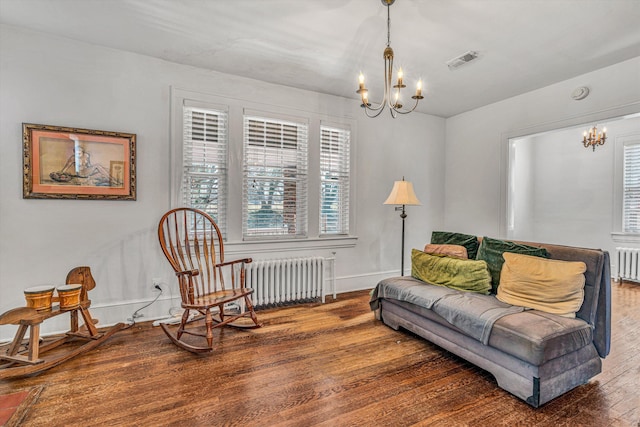 sitting room with dark hardwood / wood-style flooring, radiator, and an inviting chandelier