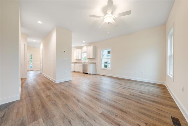 unfurnished living room with plenty of natural light, ceiling fan, sink, and light hardwood / wood-style flooring