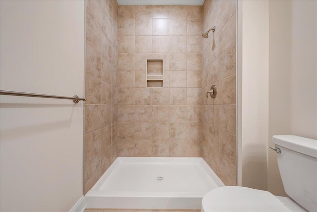 bathroom with tiled shower and toilet