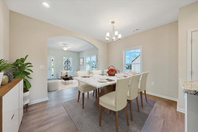 dining room featuring ceiling fan with notable chandelier and light hardwood / wood-style flooring