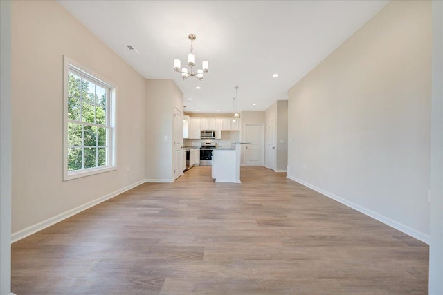 unfurnished living room with light hardwood / wood-style floors and an inviting chandelier