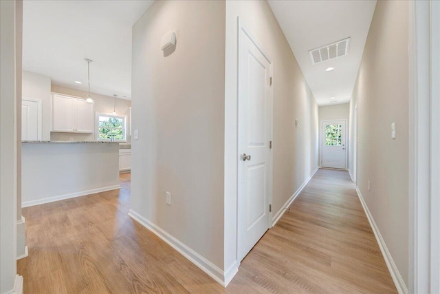 hallway with light hardwood / wood-style flooring and a healthy amount of sunlight