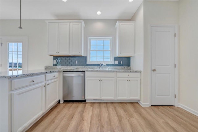 kitchen with white cabinets, stainless steel dishwasher, light wood-type flooring, tasteful backsplash, and kitchen peninsula