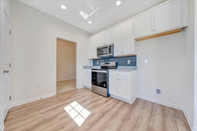 kitchen with white cabinets, light hardwood / wood-style floors, backsplash, and appliances with stainless steel finishes