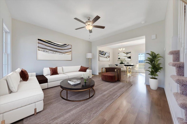 living room with hardwood / wood-style floors and ceiling fan with notable chandelier