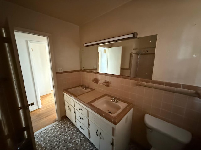 bathroom featuring vanity, toilet, and tile walls