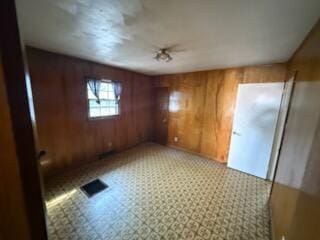 unfurnished room featuring wooden walls