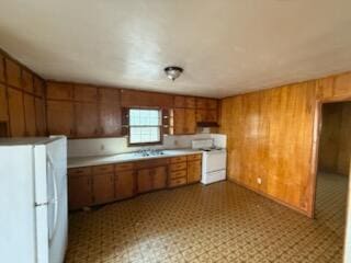 kitchen featuring white appliances, ventilation hood, and wood walls