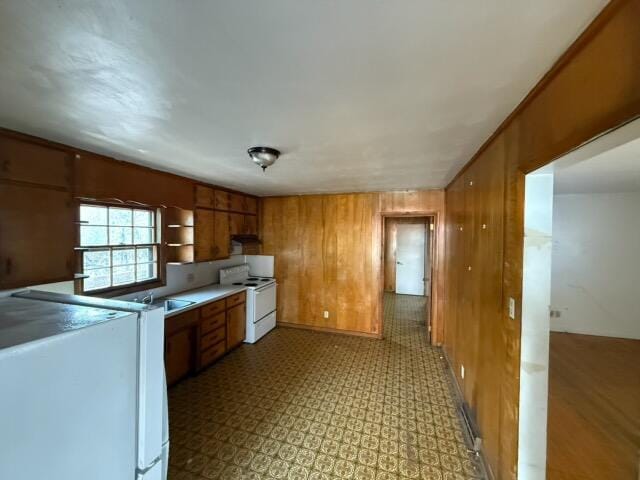 kitchen with wooden walls, white electric range oven, and sink