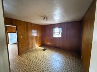 unfurnished room featuring wood walls