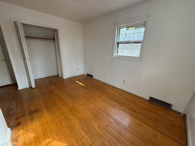 unfurnished bedroom featuring wood-type flooring and a closet