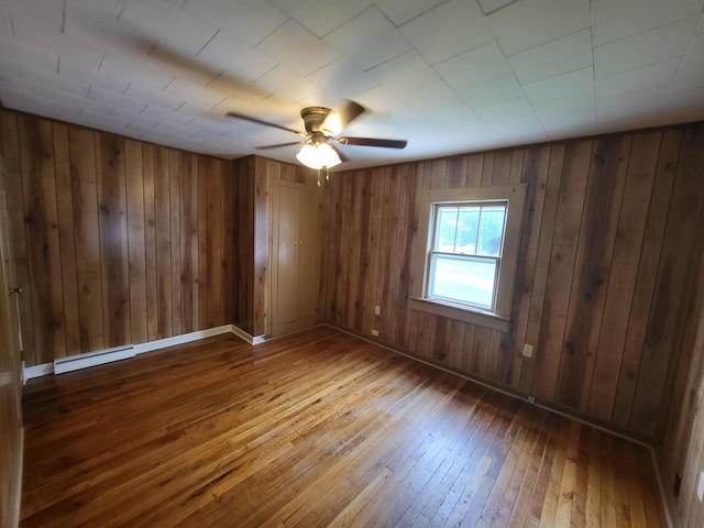 unfurnished room featuring hardwood / wood-style floors, ceiling fan, and a baseboard heating unit