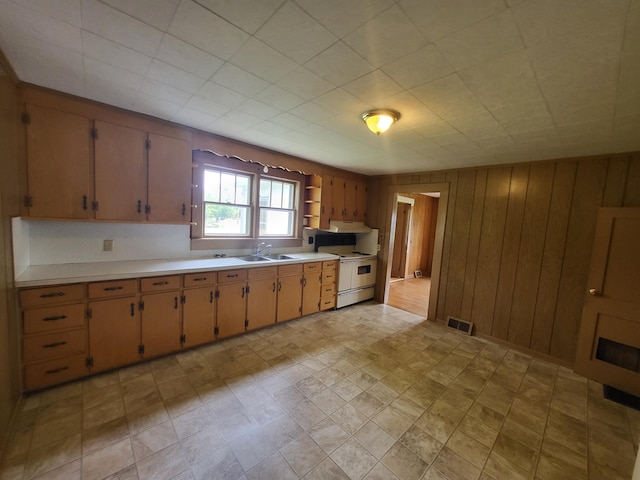 kitchen featuring wood walls, white range oven, and sink