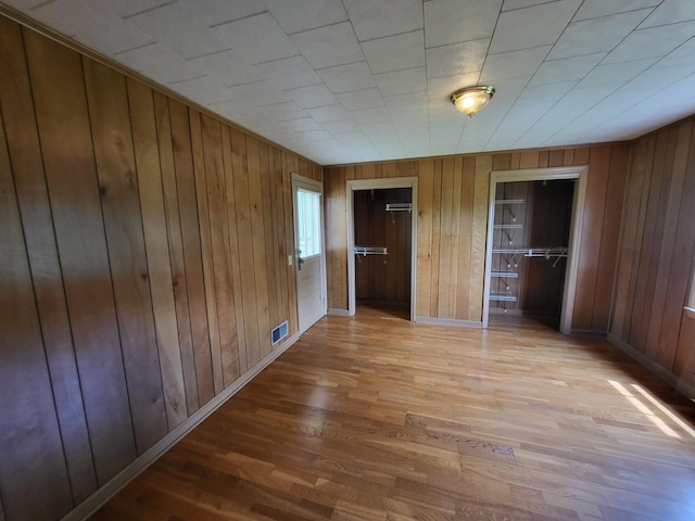 unfurnished bedroom with wood walls and hardwood / wood-style floors