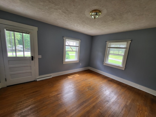 interior space with hardwood / wood-style floors, baseboard heating, and a textured ceiling