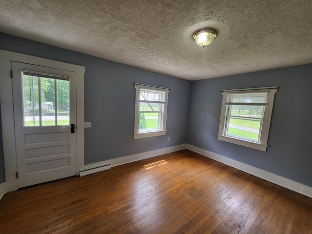 interior space with hardwood / wood-style flooring, baseboard heating, and a textured ceiling