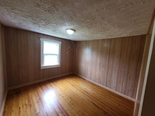 unfurnished room with hardwood / wood-style floors and wooden walls