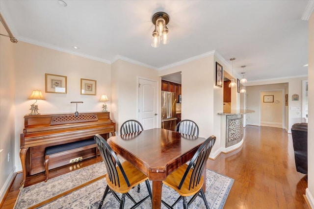 dining area with light hardwood / wood-style floors and crown molding