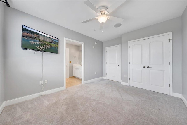 unfurnished bedroom with ensuite bathroom, light carpet, and ceiling fan