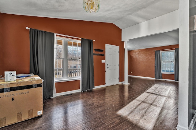 foyer featuring decorative columns, dark wood-type flooring, a healthy amount of sunlight, and vaulted ceiling