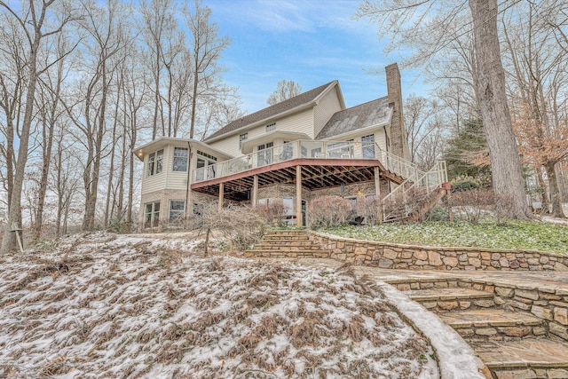 snow covered rear of property with a wooden deck