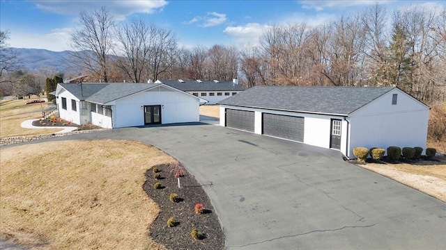 view of front of property with a garage, a mountain view, and a front lawn