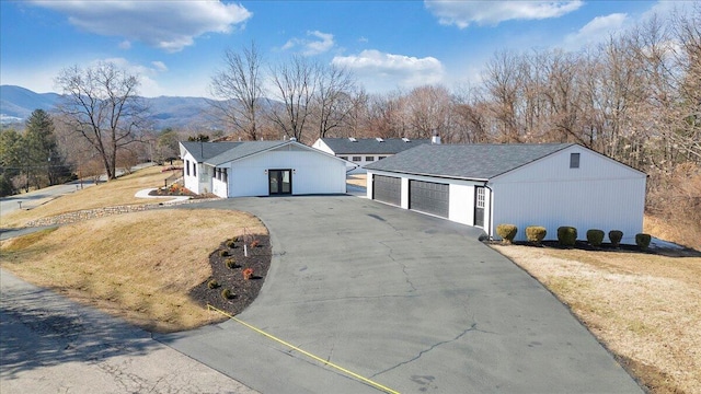 view of front facade featuring a garage, a mountain view, and a front yard