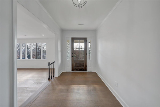 foyer entrance featuring hardwood / wood-style flooring, a wealth of natural light, and ornamental molding