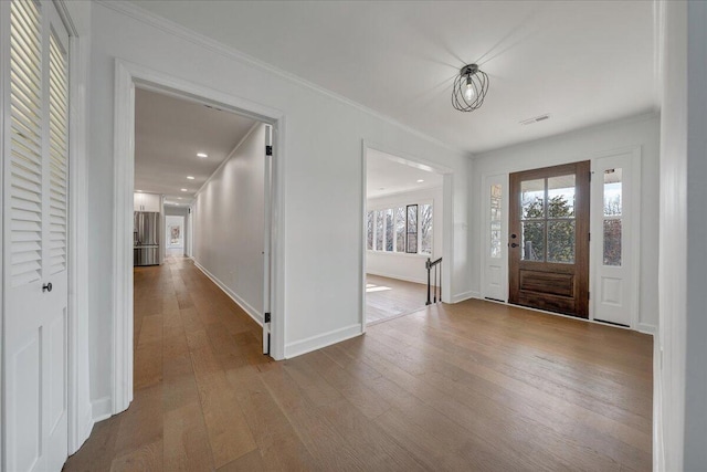 foyer entrance featuring ornamental molding and light hardwood / wood-style flooring