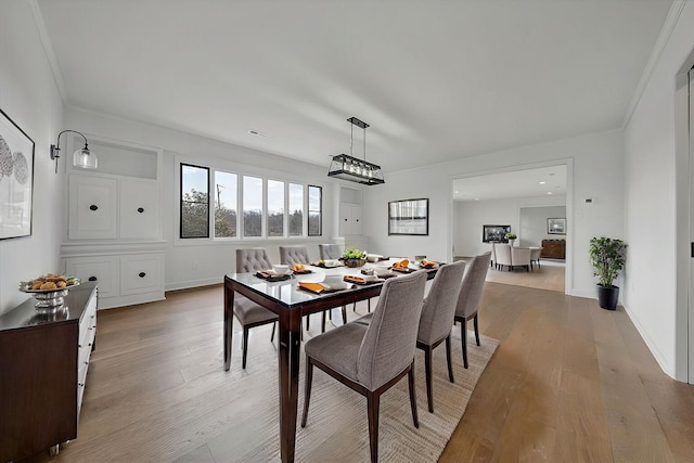 dining space featuring crown molding and light hardwood / wood-style floors