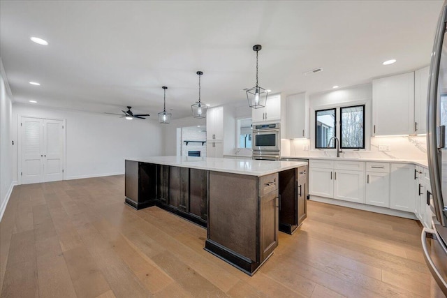 kitchen with decorative light fixtures, light hardwood / wood-style flooring, a center island, and white cabinets