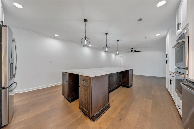 kitchen with pendant lighting, stainless steel refrigerator with ice dispenser, dark brown cabinetry, white cabinets, and a kitchen island