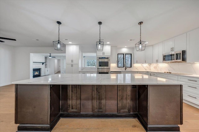 kitchen featuring stainless steel appliances, white cabinetry, decorative light fixtures, and a spacious island